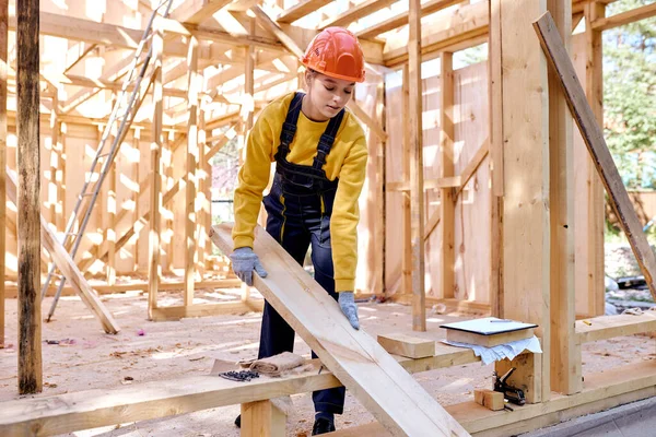 Wanita yang percaya diri bekerja di situs konstruksi kayu, mengenakan pakaian seragam yang bekerja — Stok Foto