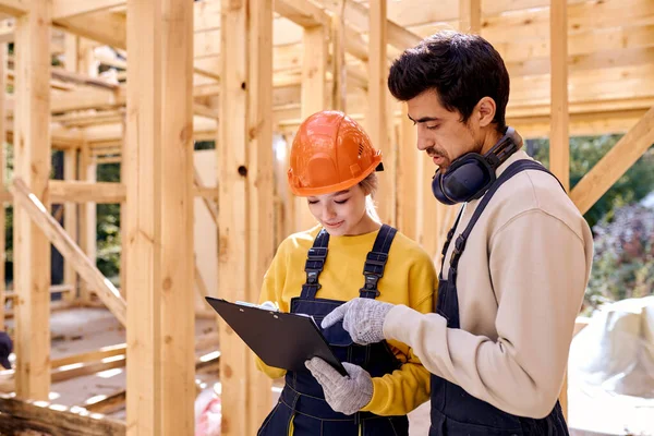 Dos ingenieros trabajadores vestidos de uniforme exploran la documentación de construcción —  Fotos de Stock