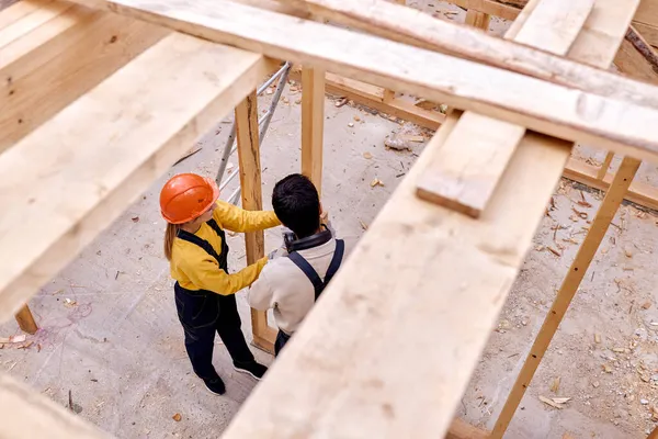 Zwei erfahrene Bauarbeiter arbeiten zusammen und bauen Holzhäuschen. — Stockfoto