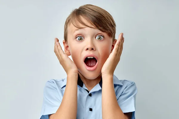 Pequeño niño sorprendido tocando la cara con la boca abierta aislado fondo de color gris — Foto de Stock