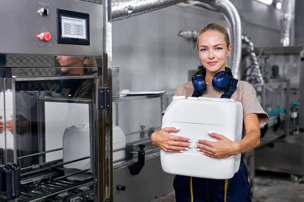 Vrouw werknemer in de fabriek naast robotapparatuur vasthouden fles — Stockfoto