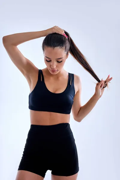 Portret van mooie jonge fitte vrouw poseren in sportkleding tegen witte achtergrond — Stockfoto