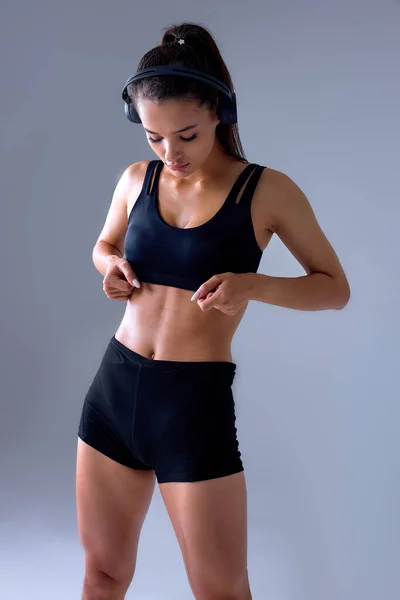 Magabiztos sportnő mutatja préskocka nélkül zsír a test fekete felső melegítőben. — Stock Fotó