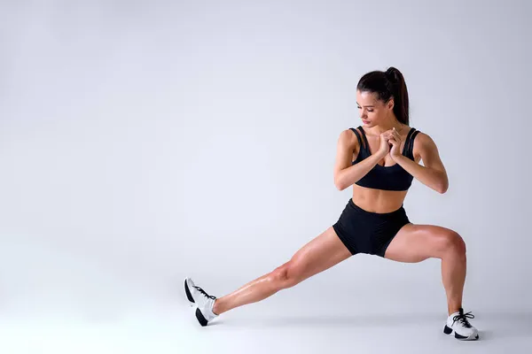 Saludable caucásico ajuste hembra en ropa de deporte haciendo saltos en estudio sobre fondo blanco — Foto de Stock