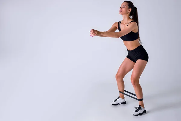 Mujer atlética deportiva caucásica en ropa deportiva haciendo ejercicio con banda elástica aislada —  Fotos de Stock