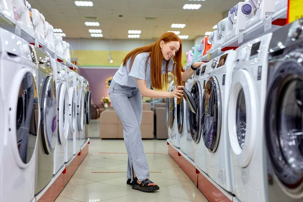 Woman buying new clothes washer in supermarket, choosing the best and the most modern