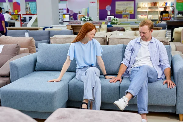 Ehepaar sitzt zusammen auf neuem Sofa im Geschäft und trifft die Wahl — Stockfoto