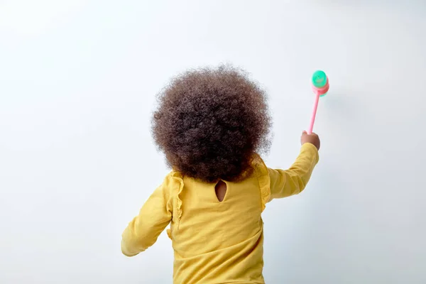 Visão traseira na menina pequena da criança que joga com brinquedo plástico, islated no fundo branco — Fotografia de Stock