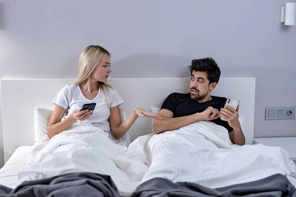 Infidelidad. Infiel marido mensajes de texto en el teléfono con el amante ignorando infeliz esposa celosa — Foto de Stock