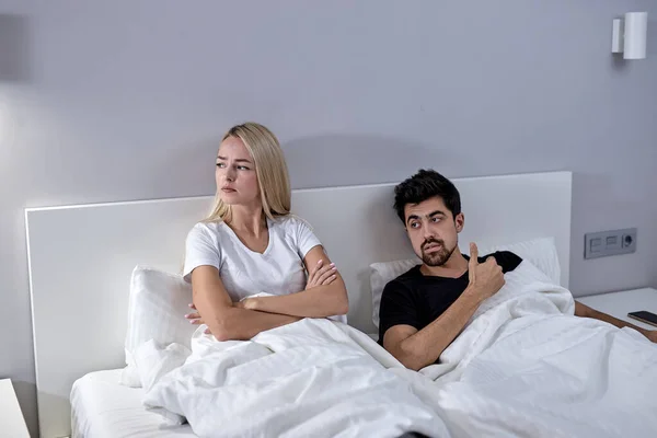 Mujer joven infeliz y el hombre no hablando después de la pelea, en la cama en casa —  Fotos de Stock