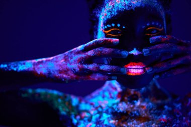 Cildinde floresan izleri, neon lambalarda parlayan kozmik boyası olan siyah bir kadın.