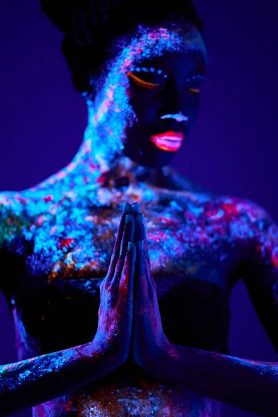 Modelo de moda mujer en luz de neón, modelo con maquillaje fluorescente en posición de oración —  Fotos de Stock