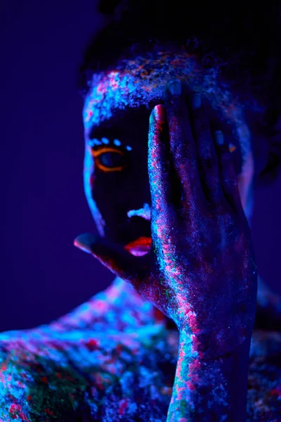 Joven hembra negra con impresiones fluorescentes en la piel, pintura cósmica que brilla sobre luces de neón —  Fotos de Stock