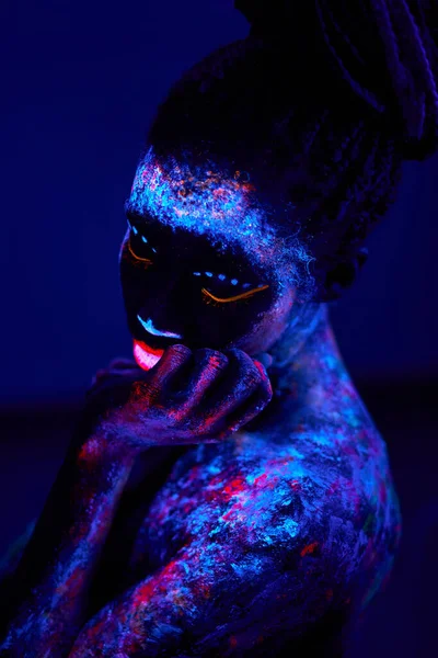 Mujer nativa americana con maquillaje de neón, hecha de pintura fluorescente en luz ultravioleta. —  Fotos de Stock