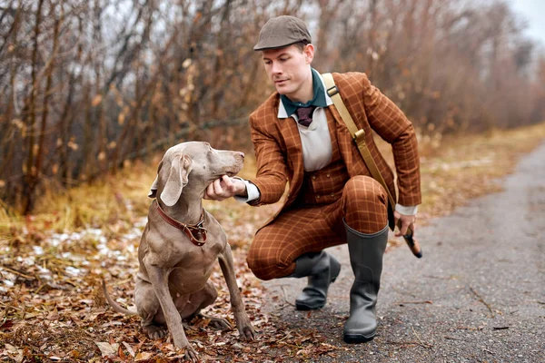 森の中の若いオスハンター銃を持って犬と歩く男。犬が撃たれるのを待ってる — ストック写真