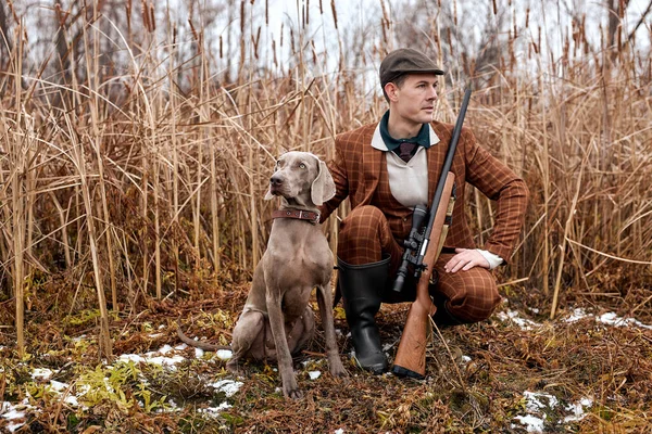 Hombre con perro sentado en los arbustos y cazando un animal, en la naturaleza salvaje — Foto de Stock