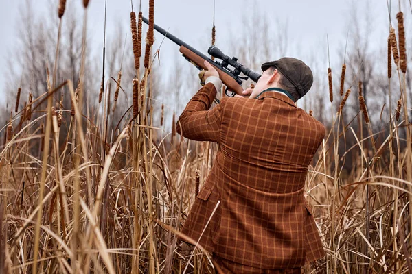 Mladý lovec loví v lese, dívá se přes pušku, měkké zaměření. na venkově — Stock fotografie