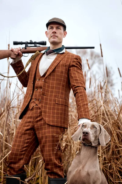 Retrato de chico guapo en traje con perro gris en la caza, mirando al lado. vista hacia abajo —  Fotos de Stock