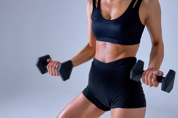 Sportswoman doing workout with dumbbells isolated over grey studio background — Stock Photo, Image