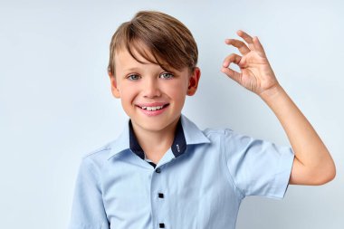 Sorun değil. Mutlu çocuk iyi bir jest yapıyor, beyaz stüdyo geçmişinde izole edilmiş.