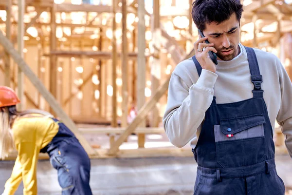 Bouleversé architecte constructeur homme parler au téléphone contre Nouvelle construction résidentielle cadrage de la maison — Photo