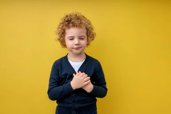 Tranquilo Niño lindo cogido de la mano en el pecho cerca del corazón. Concepto de emociones humanas — Foto de Stock