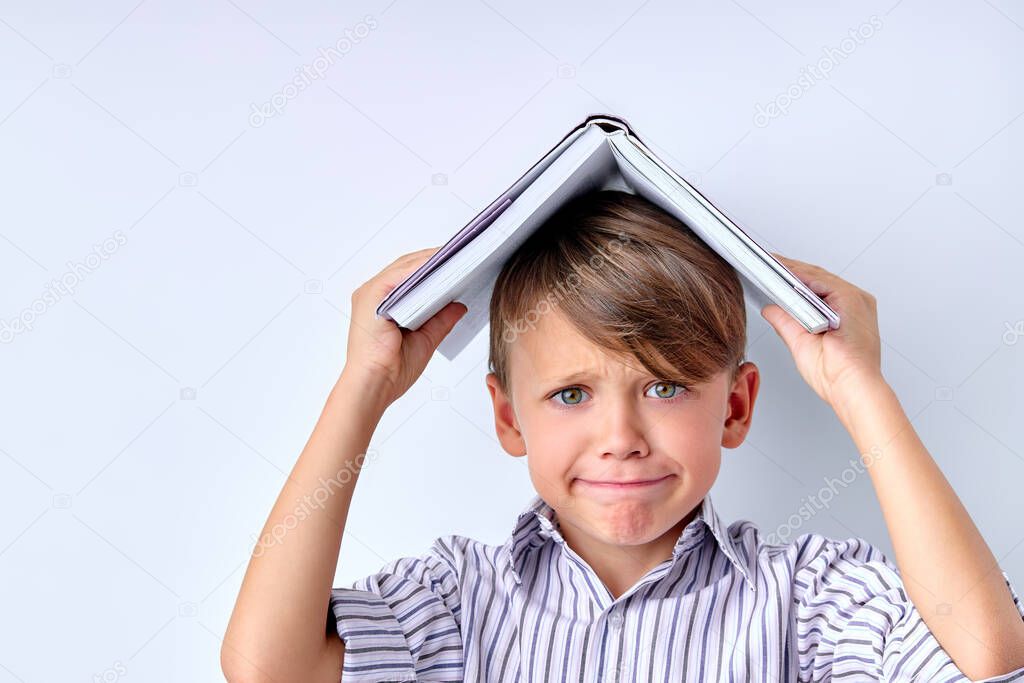 School Child Boy with Book on Head on White Studio Background Copy Space.