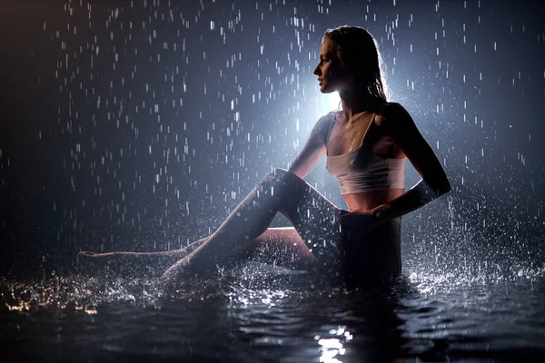 Retrato da vista lateral da silhueta magro da mulher que posa sob a chuva, molhado e sensual — Fotografia de Stock