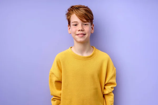 Verlegen en ijverig tiener jongen kijken naar camera, glimlachen, geïsoleerd op paarse achtergrond — Stockfoto
