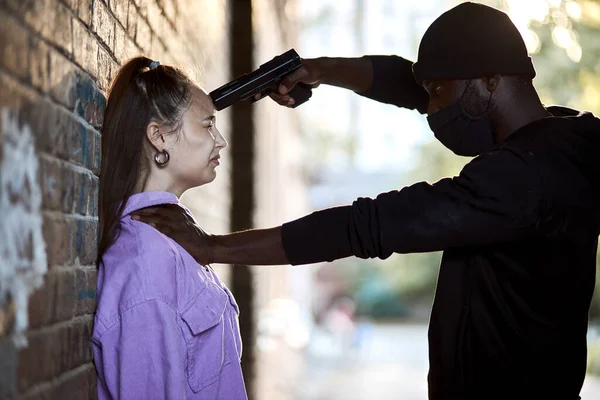 Rape victim sad frightened woman is leaned on wall, gun-threatened by maniac in dark tunnel — Stock Photo, Image