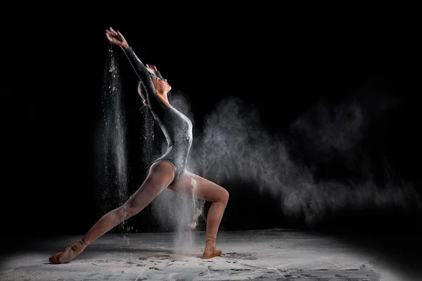 Flexibilní baletní tanečnice žena tanec a sypat mouku na černém pozadí — Stock fotografie