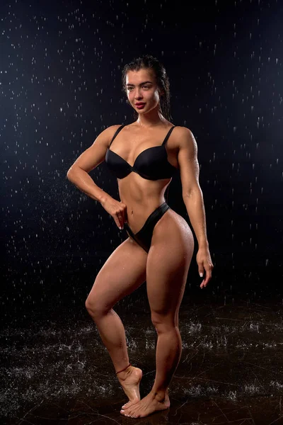 Piękna mokra wysoka szczupła kobieta w czarnej bieliźnie pozująca w kroplach wody deszczowej — Zdjęcie stockowe