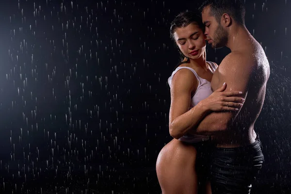Нежные объятия. Сексуальная кавказская пара, здоровые мужчина и женщина обнимаются под дождем — стоковое фото