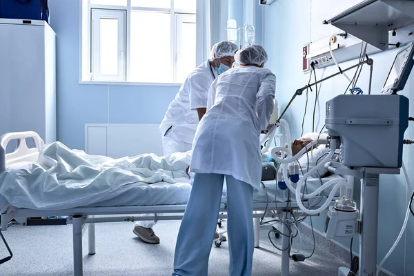Two friendly doctors nurses help injured sick person, in hospital ward room