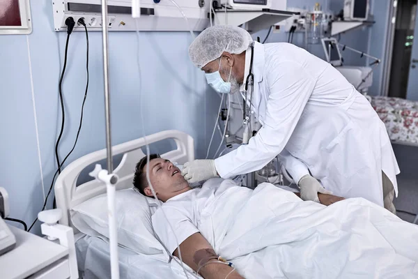 Ung skadad man ligger i sängen sjukhusrum i dåligt hälsotillstånd — Stockfoto