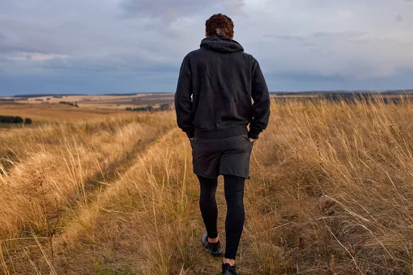 Kilátás hátulról férfi séta területen futás után, sportos ruhában — Stock Fotó