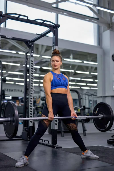 Ung passform stark kvinna gör övningar med vikt i moderna gym, ensam. — Stockfoto