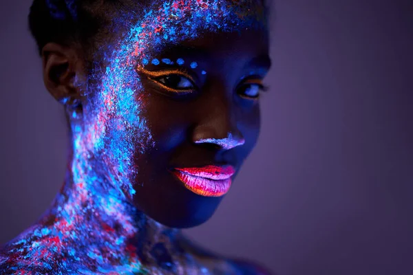 Schwarze Hündin mit Körperkunst in UV-Licht. Frau mit fluoreszierendem Pulver bemalt — Stockfoto