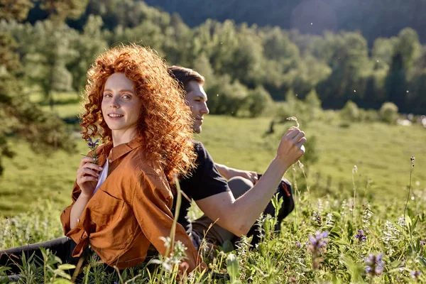 Gyönyörű pár az erdőben. Fiatal nő és férfi ül a füvön — Stock Fotó