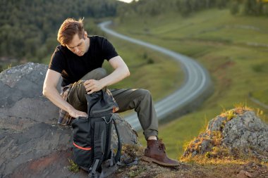 Kafkasyalı gezgin sırt çantasını boşaltıyor. Termosla çay içiyor.