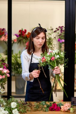 Mevsimlik çiçek buketi yapma süreci. Kadın çiçekçi iş başında.