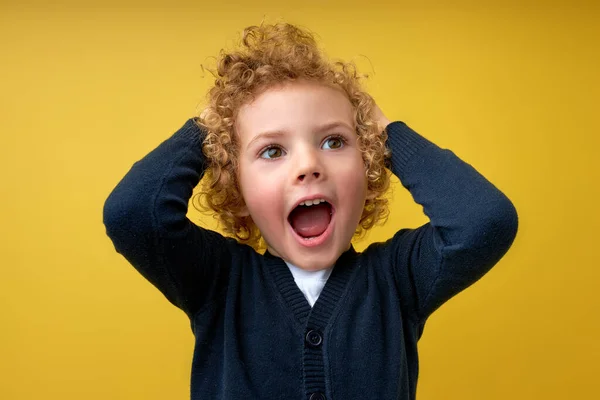 Retrato de menino com cabelo encaracolado gritando, tendo expressão louca, olhando para o lado — Fotografia de Stock