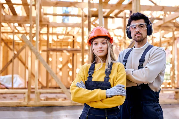 Portret van serieuze mannelijke en vrouwelijke bouwkameraden die buiten op camera poseren — Stockfoto