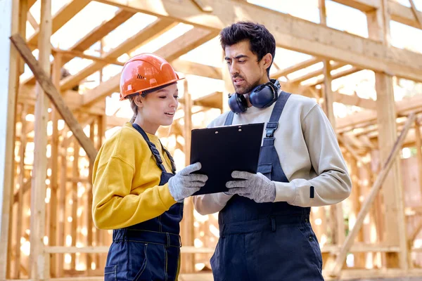 Zwei Männer und eine Frau in Uniform und Helm erkunden Bauunterlagen — Stockfoto