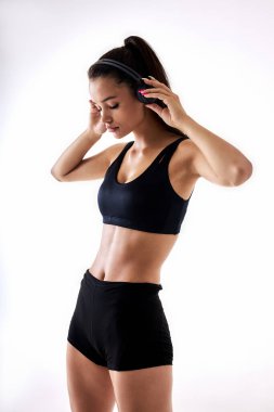 Spor yaparken siyah spor elbiseli ve kulaklıklı genç bir kadının portresi