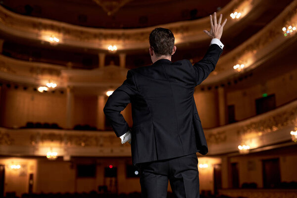 Известный американский артист стоит на сцене, приветствует зрителей, начинает представление.