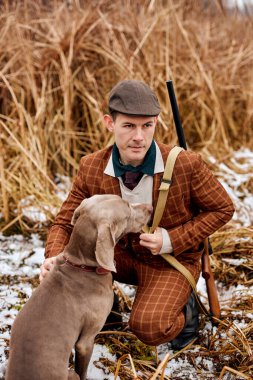 Şapkalı bir avcı ve sosisli bir köpek doğada dost. Harika bir sonbahar sabahı..