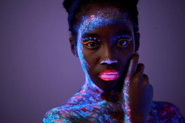 Sakin siyah model kadın neon ışığı altında. floresan makyajlı siyah model