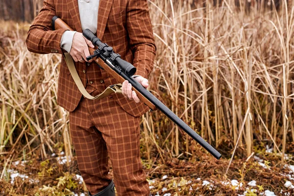 Hombre cazador recortado sosteniendo arma y caminando en el bosque. Rifle Hunter En el área rural — Foto de Stock