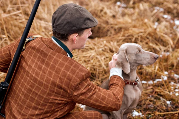 Vista trasera en macho con perro gris sentado en el campo esperando trofeo animal salvaje objetivo —  Fotos de Stock